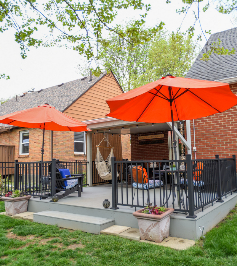 Backyard deck with orange umbrellas, hammock chair, and outdoor seating