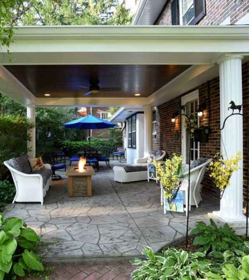 Covered patio with fire pit, wicker seating, and blue umbrella